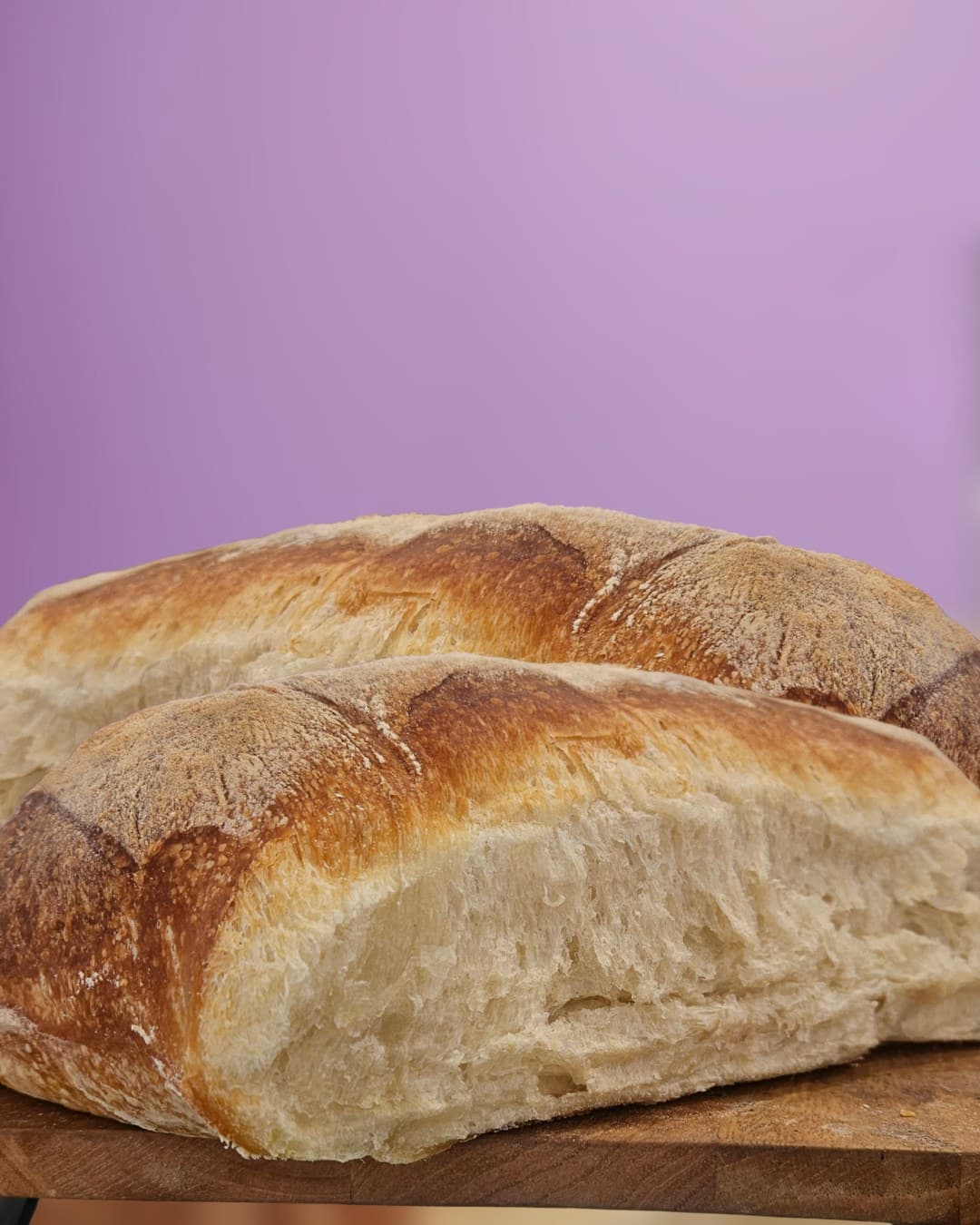 Fresh bread loaves on a warm brand colour backdrop