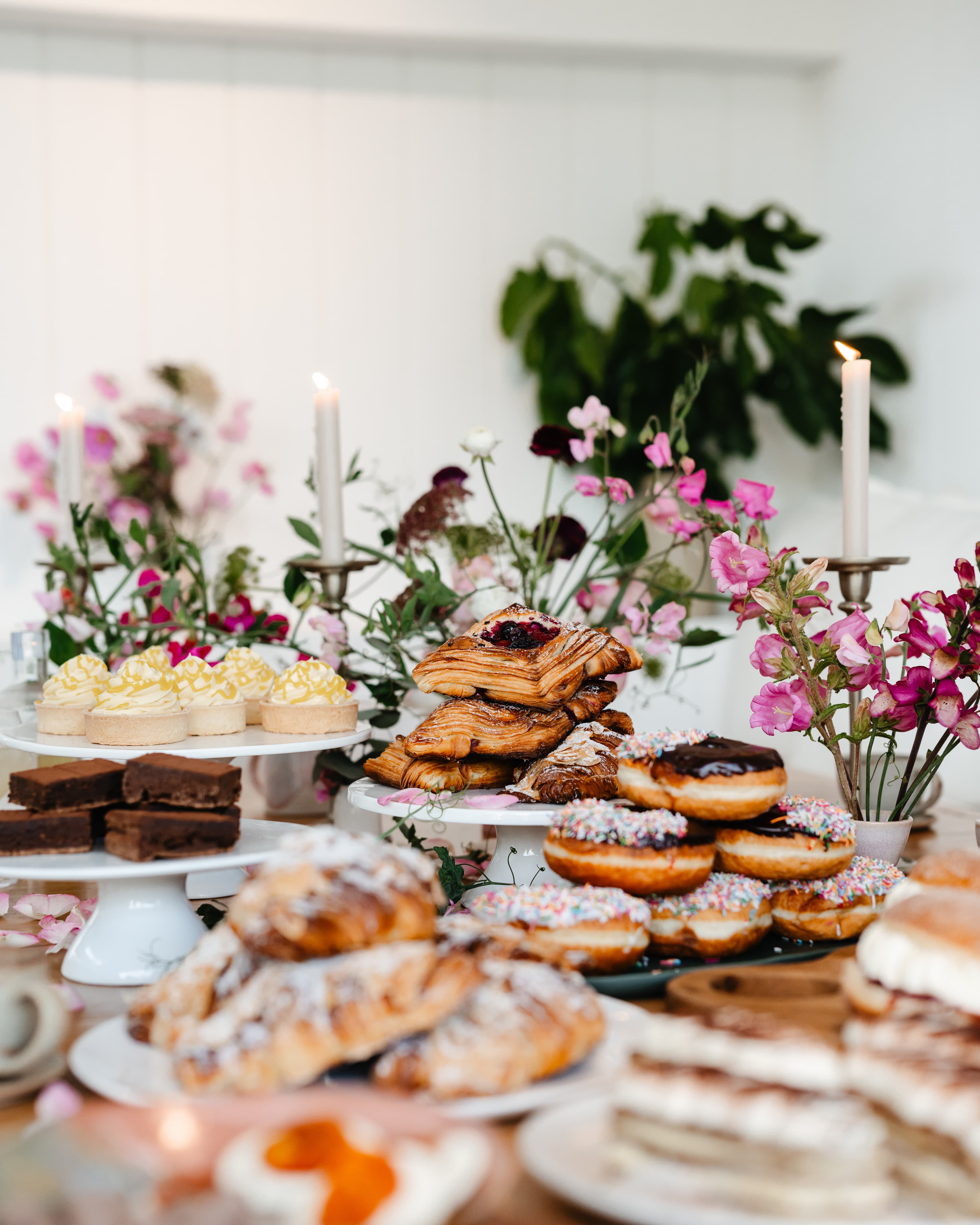 Home Grain Bakery catering spread with pastries, slices, donuts, flowers and candles